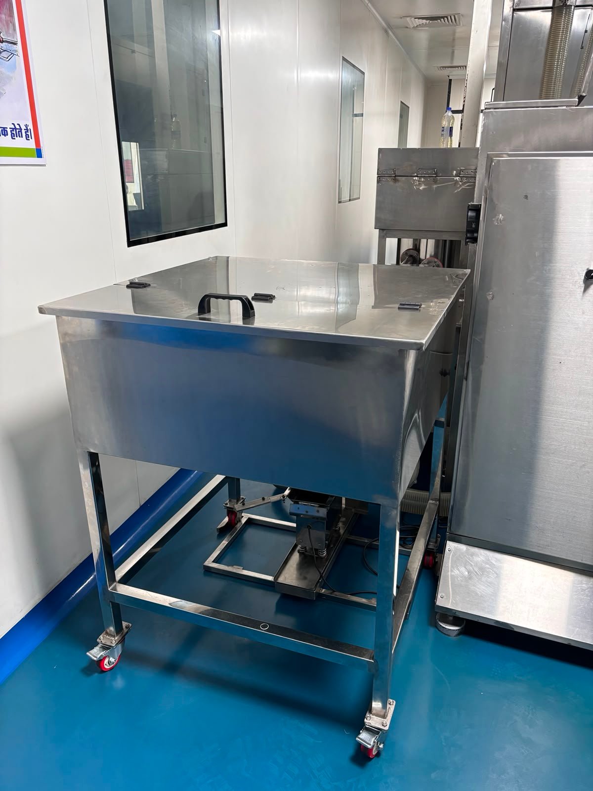 Stainless steel day bin on wheeled support inside a clean processing room