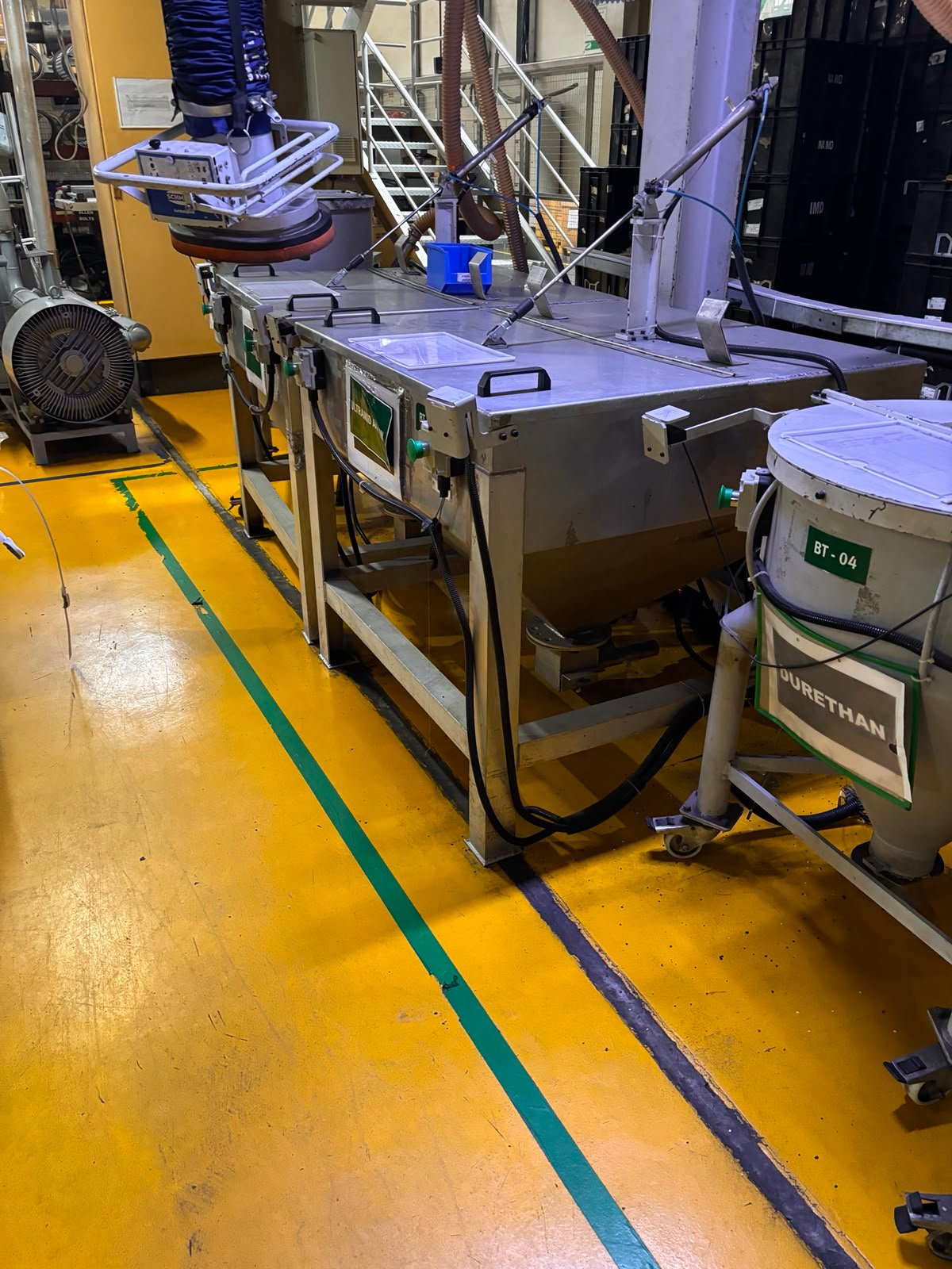 Multiple stainless steel bins and processing equipment installed on a factory floor